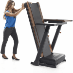 A woman wearing business work attire folding the Nordictrack Treadmill Desk