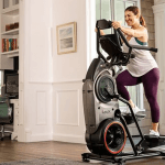 A woman in athletic attire working out on the Bowflex Max Trainer M8 in a living room setting